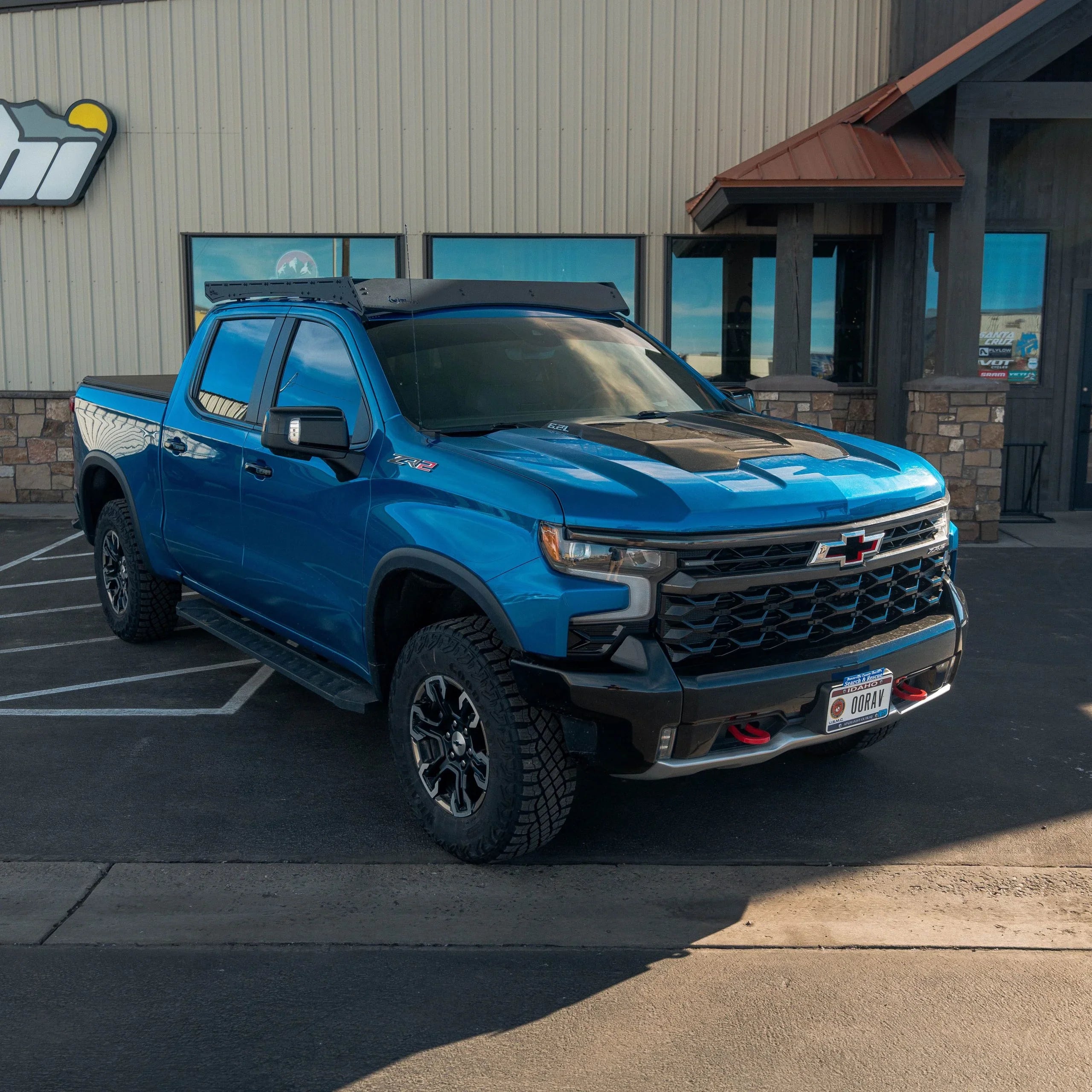 Blue Chevrolet Silverado ZR2 pickup truck with roof rack parked in front of a building