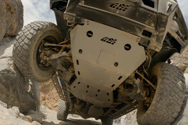 Heavy-duty skid plate installed under off-road truck driving over rocky terrain