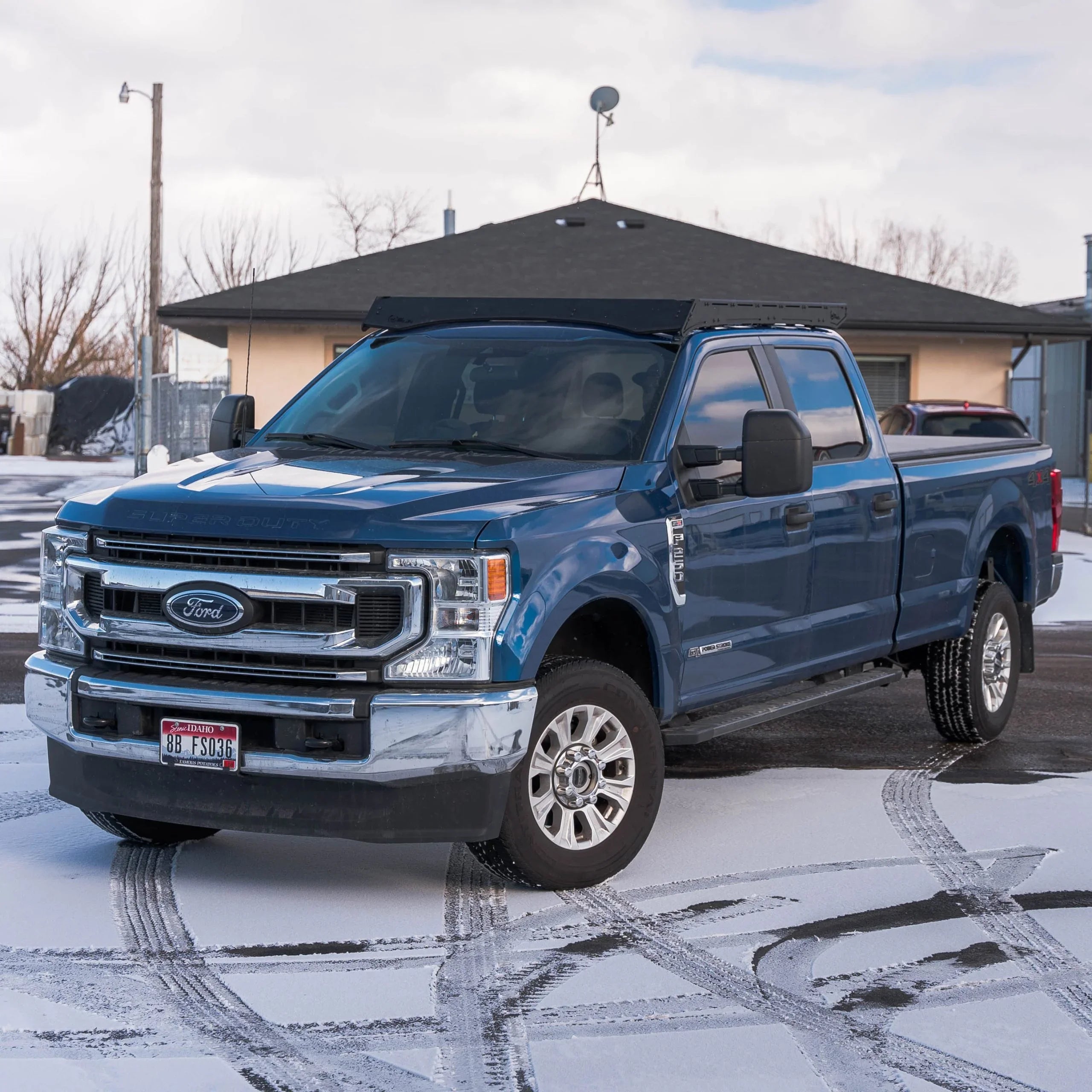 Blue Ford Super Duty truck with roof rack accessory parked on snowy pavement