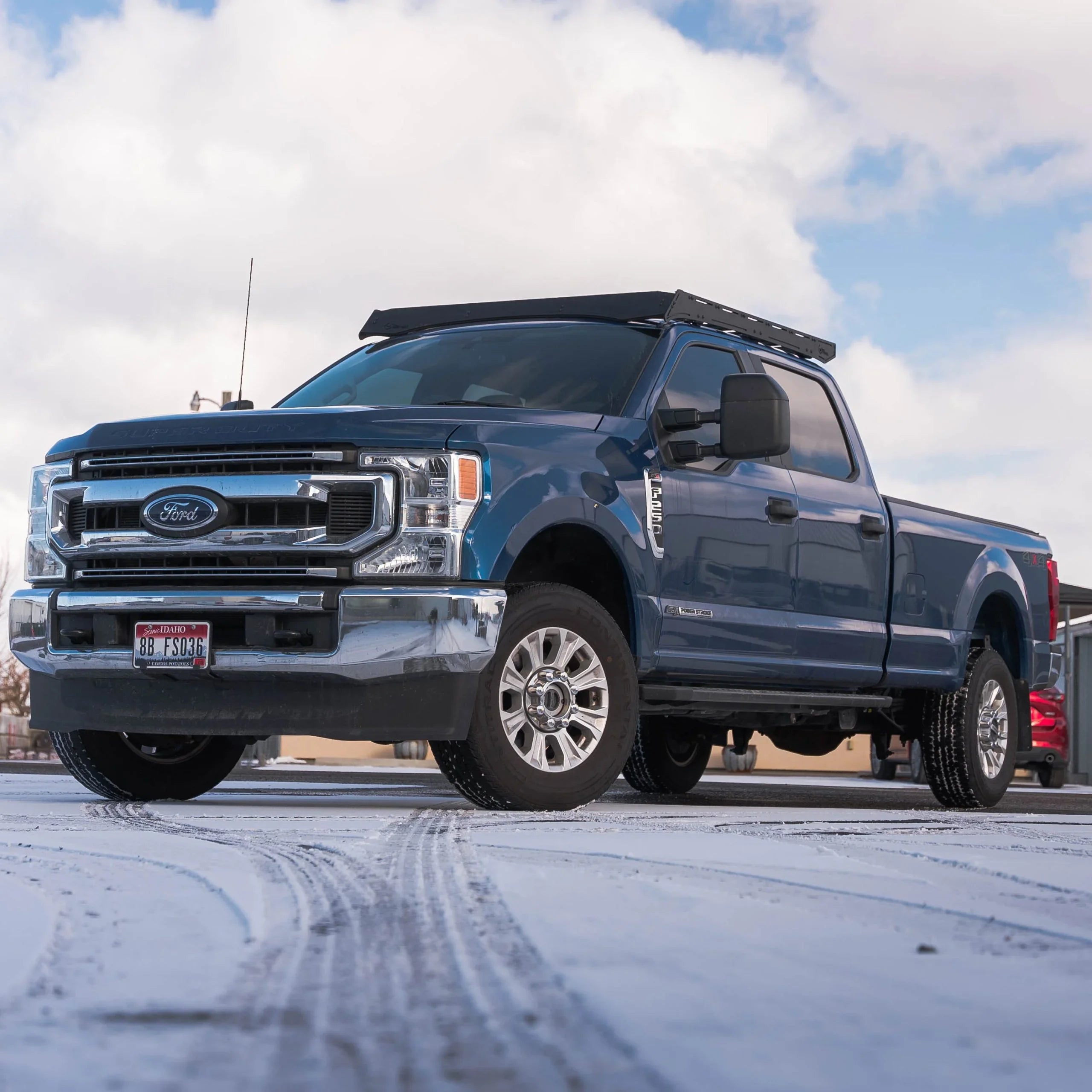 Ford Super Duty pickup truck with roof rack parked on snowy pavement outdoors
