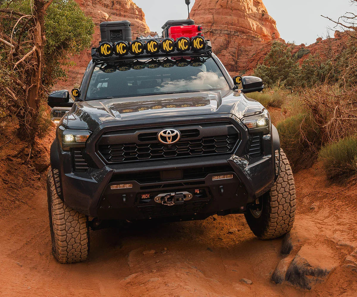 Toyota Tacoma outfitted for overlanding with off-road lights and gear in a red rock desert