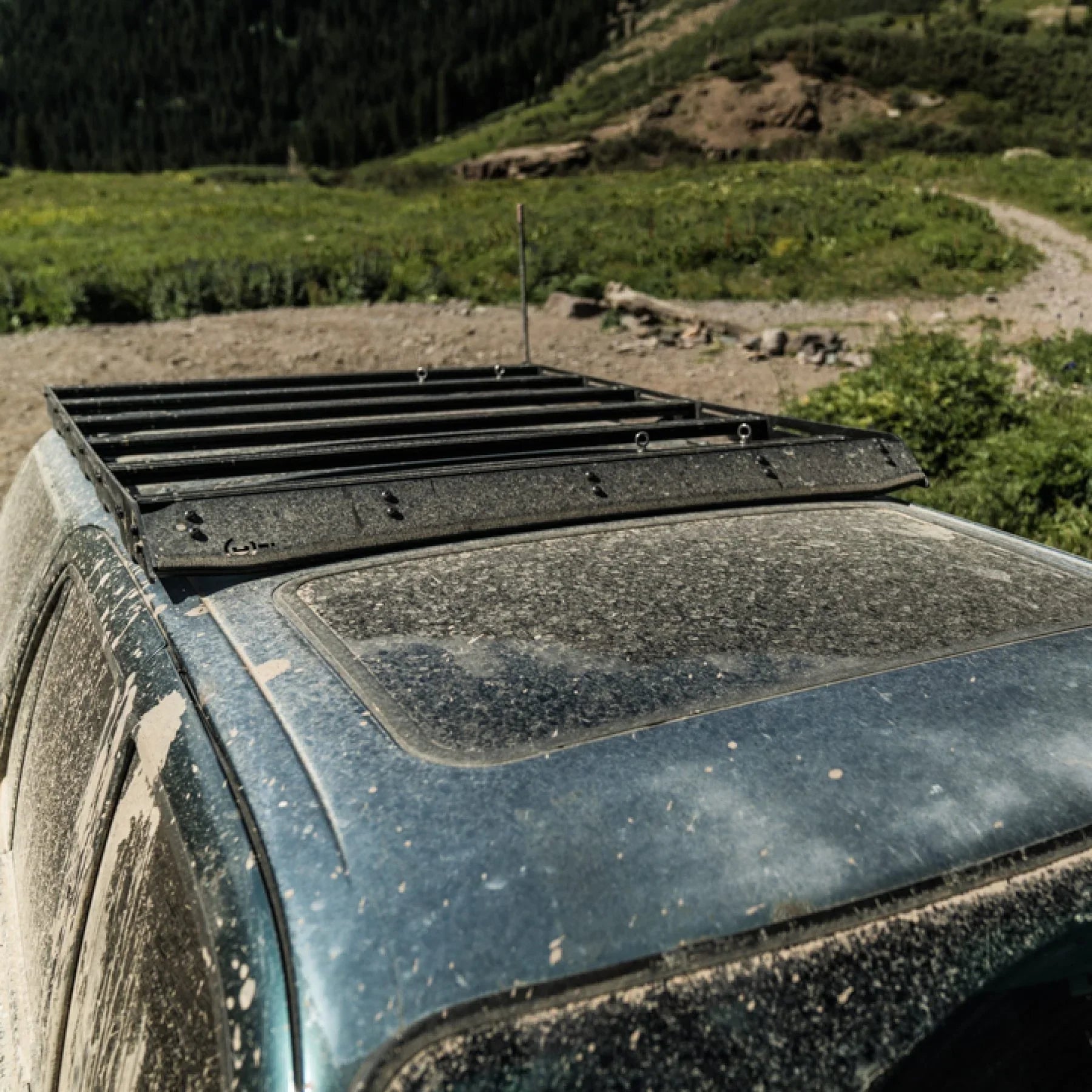 Black roof rack installed on a dusty Toyota 4Runner in an outdoor off-road setting