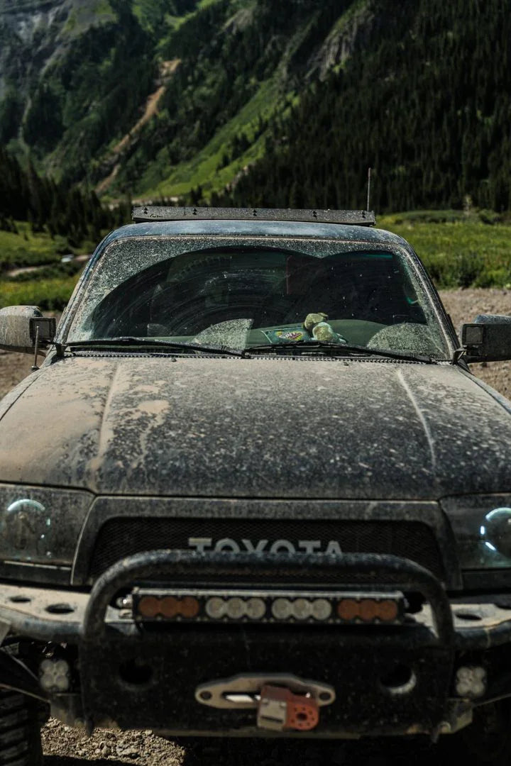 Muddy Toyota 4Runner with off-road accessories parked in a mountain landscape