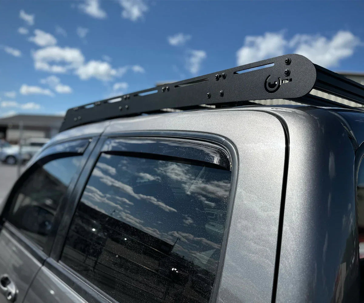 Black modular roof rack installed on a silver overland vehicle in outdoor setting