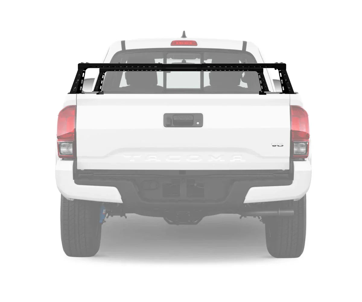 Black bed rack installed on white Toyota Tacoma pickup truck rear view