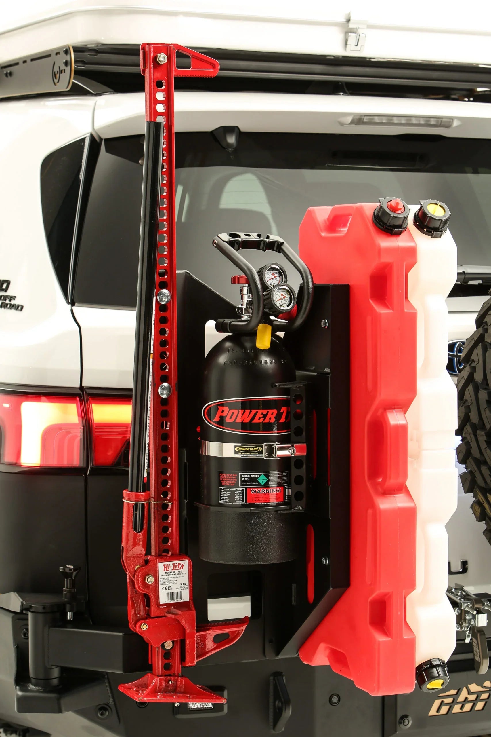 Toyota SUV rear with off-road accessories, including Hi-Lift jack, fuel canisters, CO2 tank.