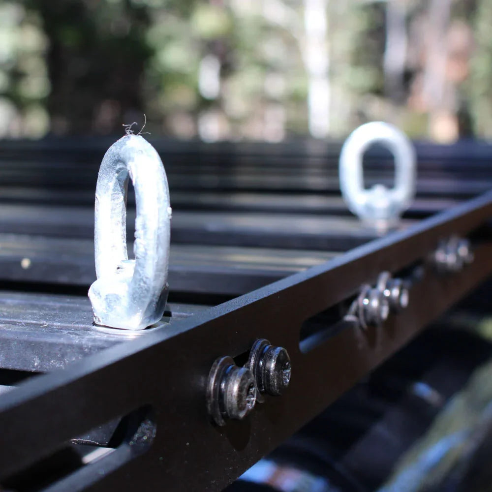 Steel tie-down eye nuts mounted on a black roof rack for overlanding vehicles