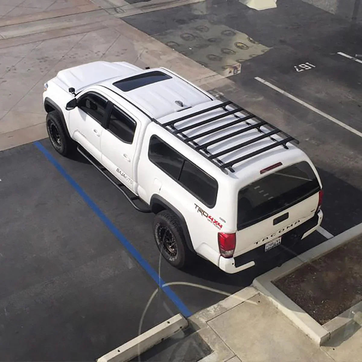 Overhead view of white Toyota Tacoma with roof rack parked in lot, ideal for overlanding gear