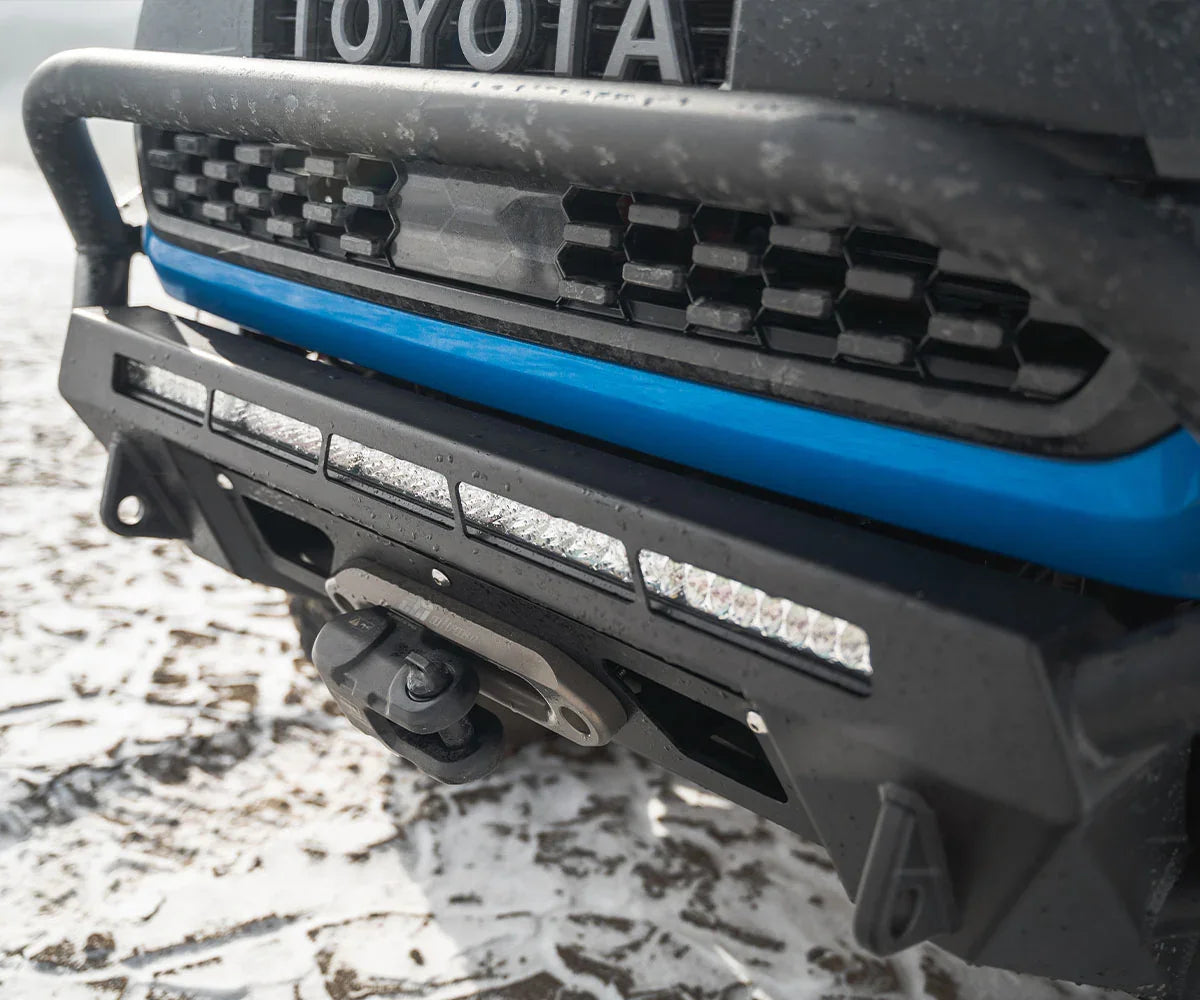 Toyota Tacoma hybrid front bumper with skid plate and LED light bar on snowy ground