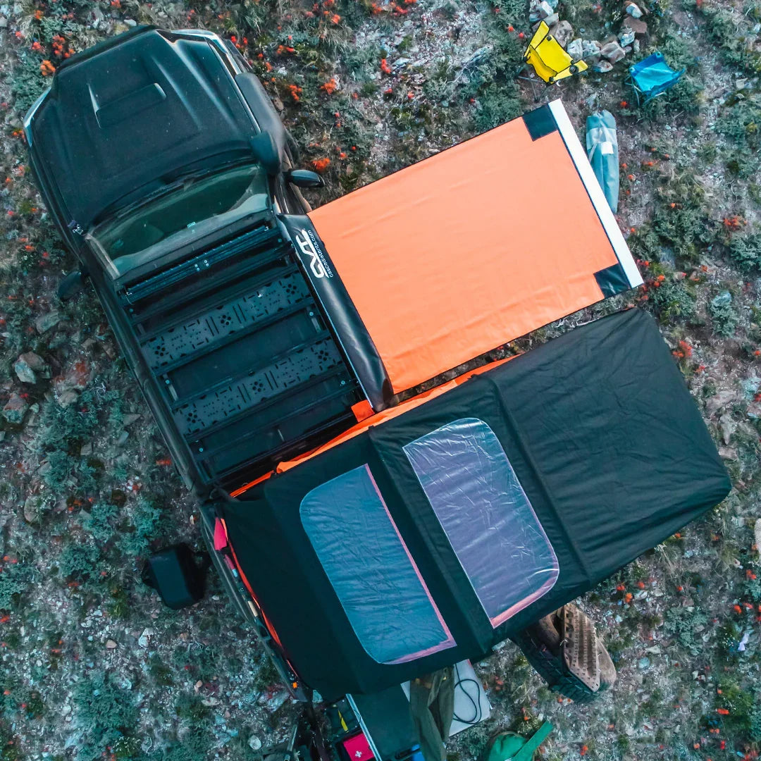 Toyota Tacoma with overland bed rack, rooftop tent, and awning set up at a campsite