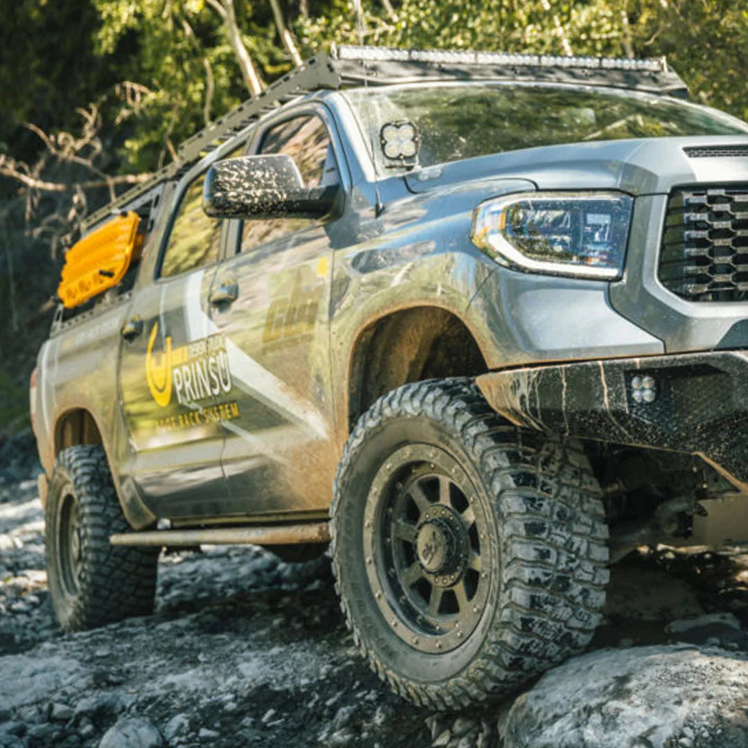 Toyota Tundra with overland rock sliders and off-road accessories on rocky terrain