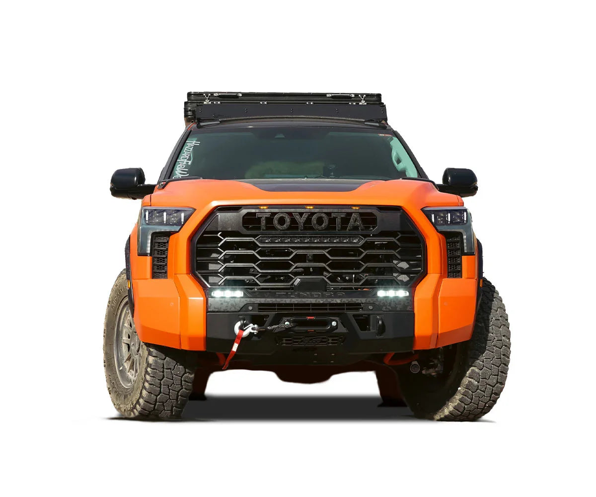 Front view of an orange Toyota Tundra with off-road bumper, winch, roof rack, and LED lights
