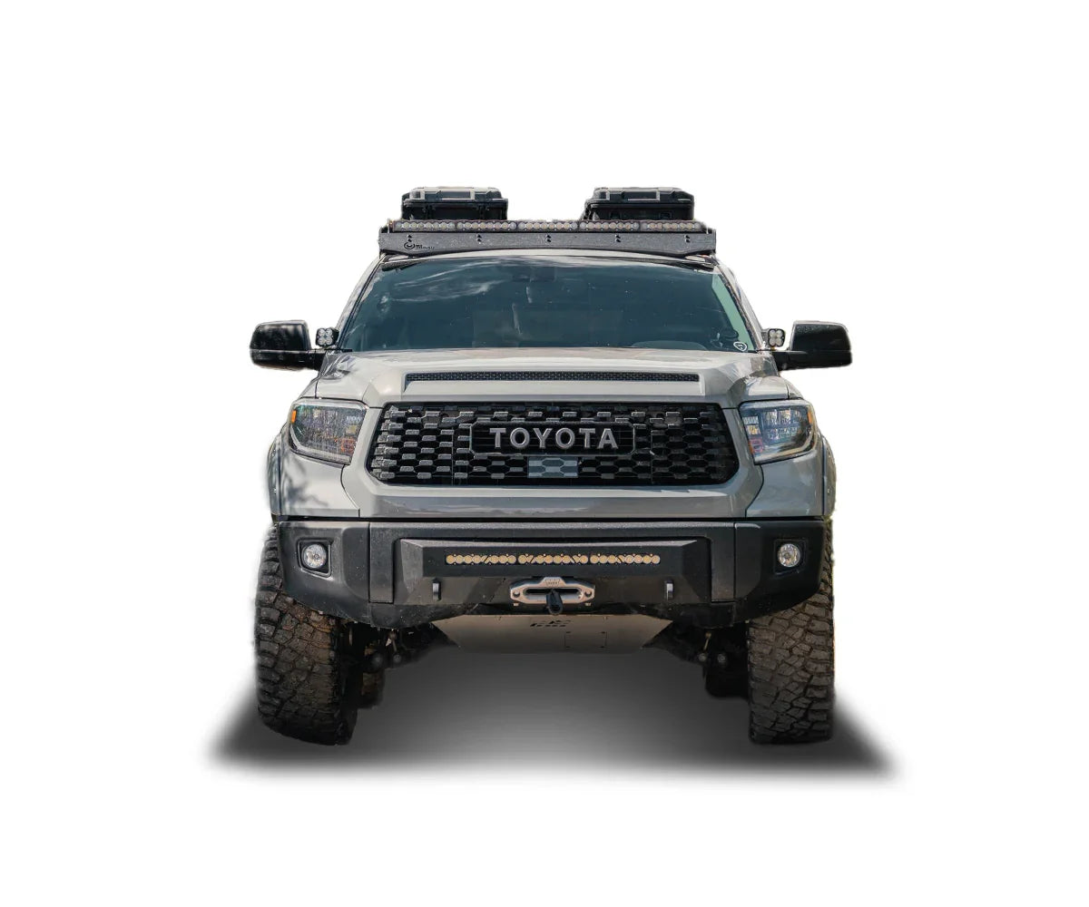 Front view of a 2018 Toyota Tundra with roof racks, off-road bumper, and adventure gear