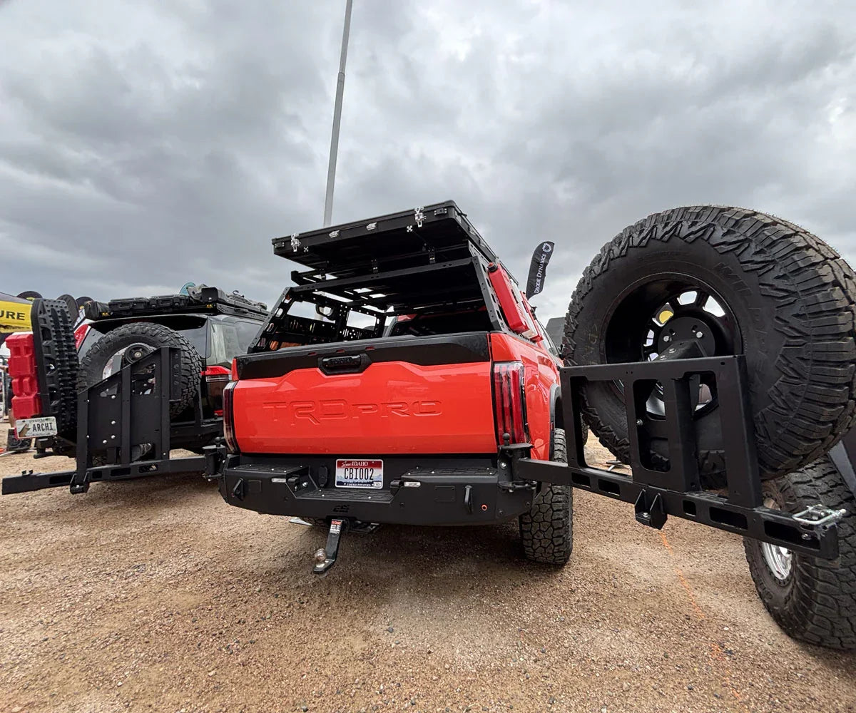 Toyota Tundra TRD Pro with overland gear, swing-out tire carrier, and roof rack at camp
