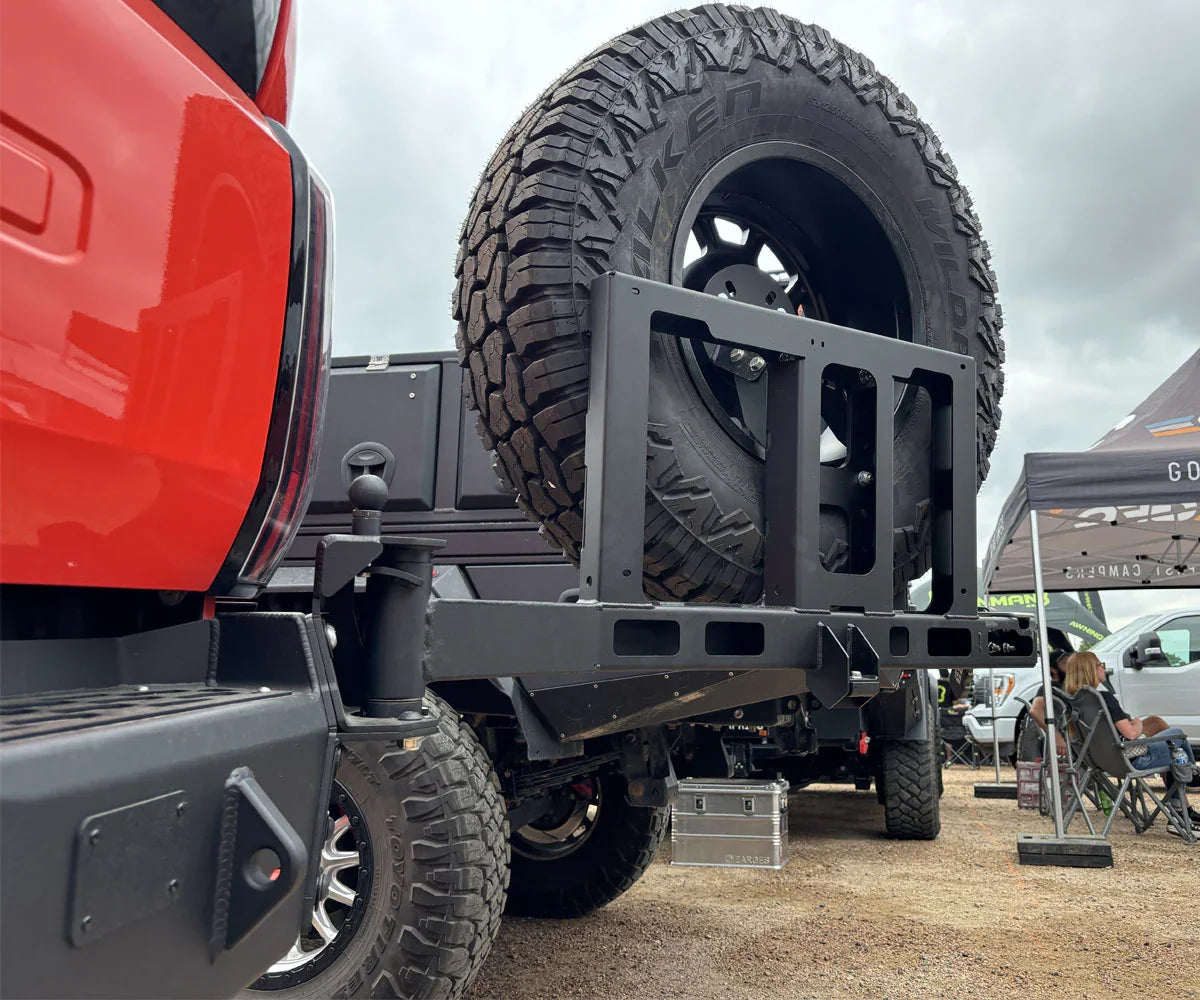 Toyota Tundra rear bumper with heavy-duty tire carrier and off-road tire at outdoor event