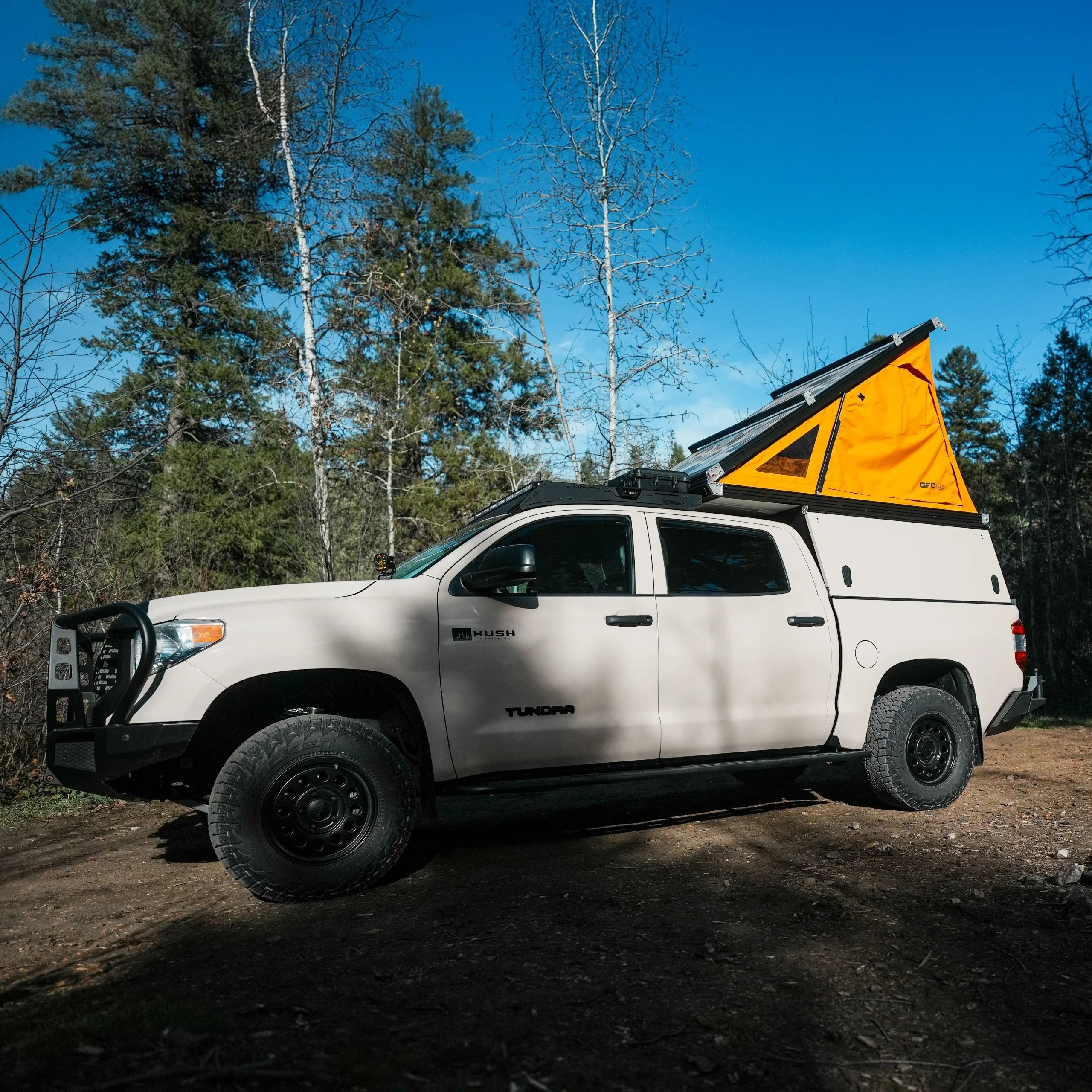 Toyota Tundra truck with rooftop camper tent in forest, ideal for overlanding and expedition camping