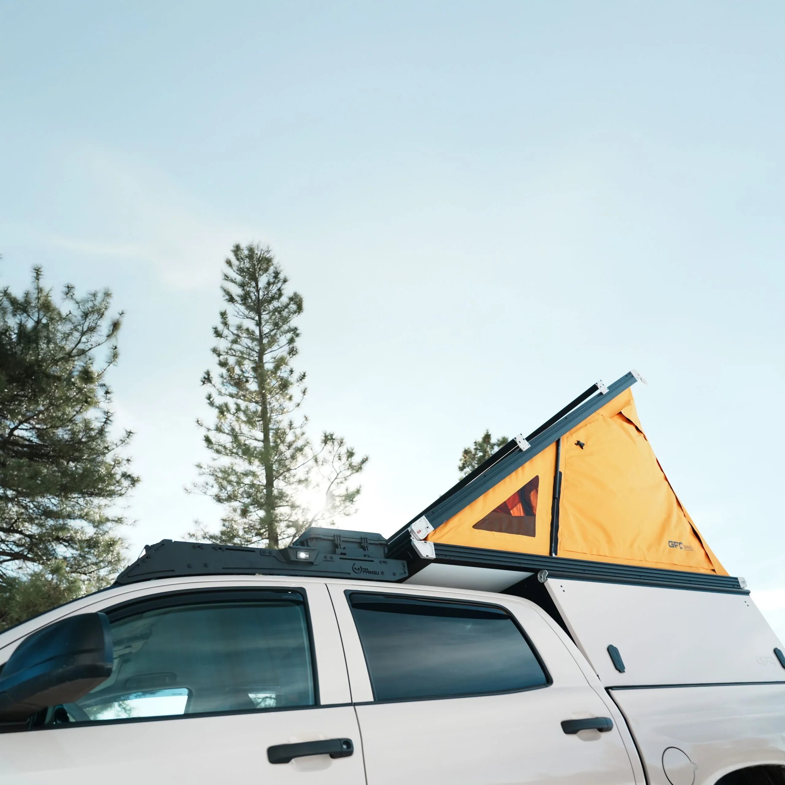 Toyota Tundra with rooftop camper tent set up for overlanding in a pine forest