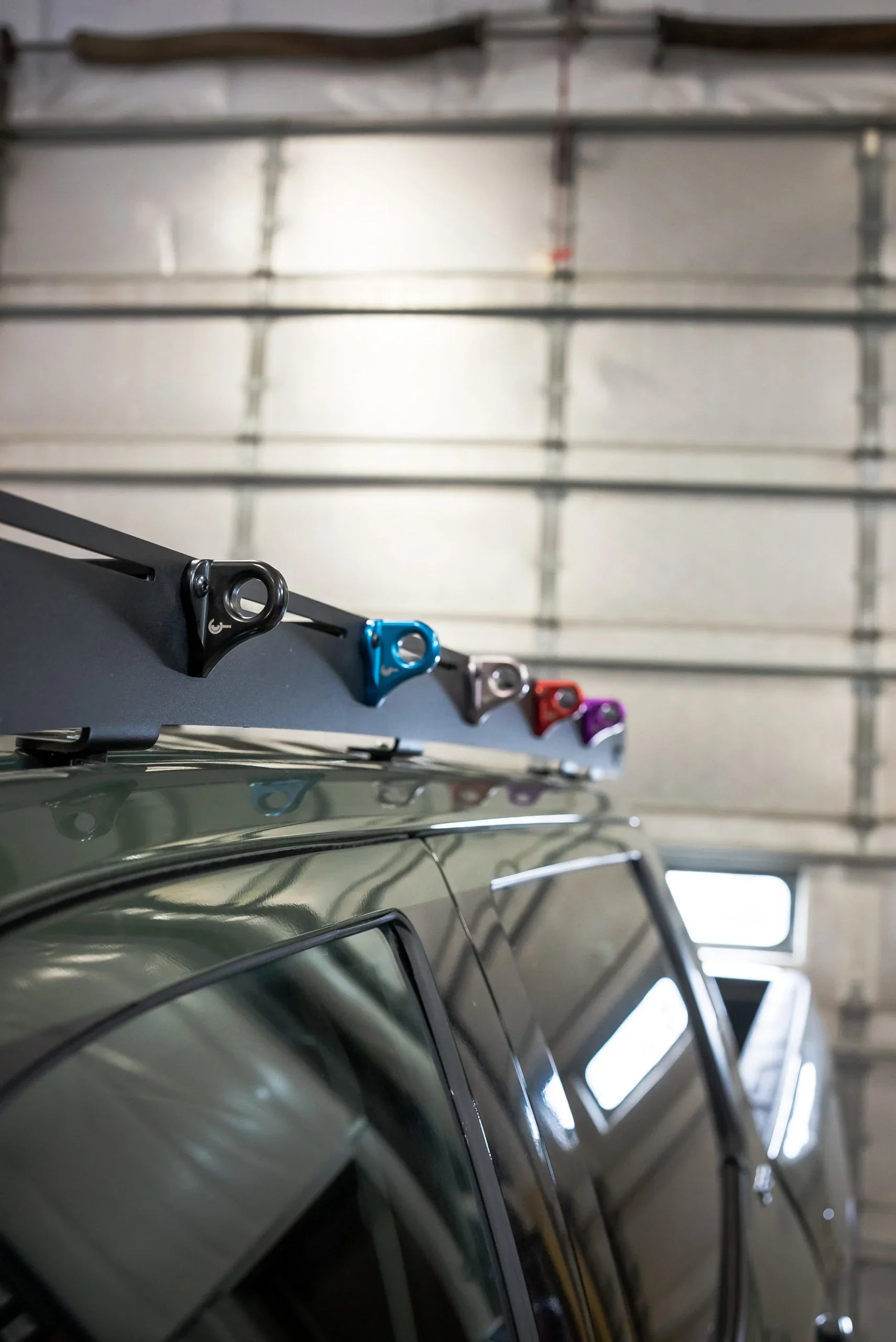 Multicolor utility hook mounts installed on a vehicle roof rack for overlanding gear