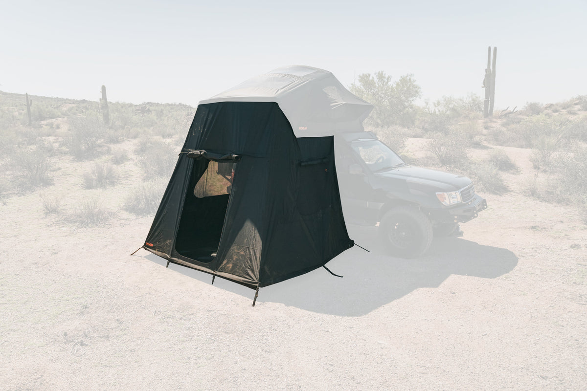 ROAM Vagabond 2.0 annex tent attached below a rooftop tent on a vehicle parked in a desert with a saguaro behind