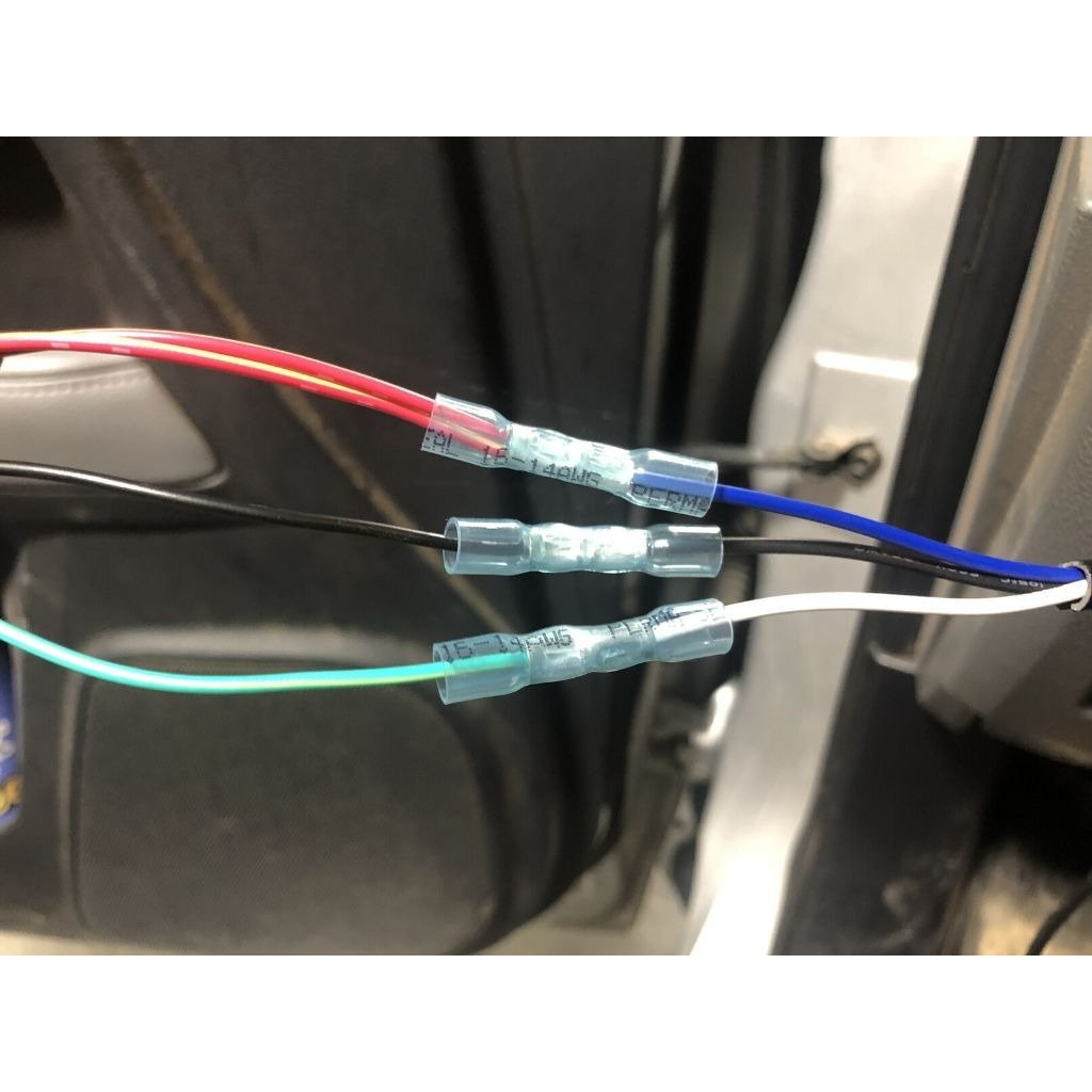 Close-up of color-coded automotive wires with heat shrink connectors in a vehicle interior