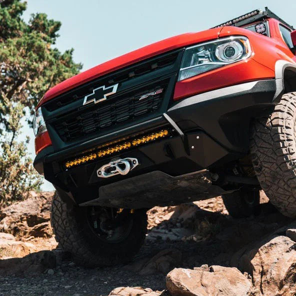Red off-road truck with bull bar and LED light bar driving over rocky terrain