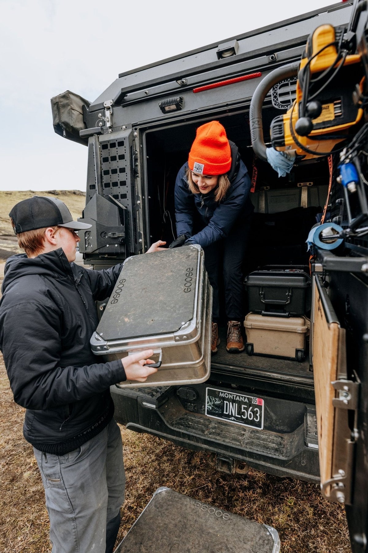 Goose Gear Alu-Box with top plate being slid out of a truck canopy by a person in an orange beanie as another looks on