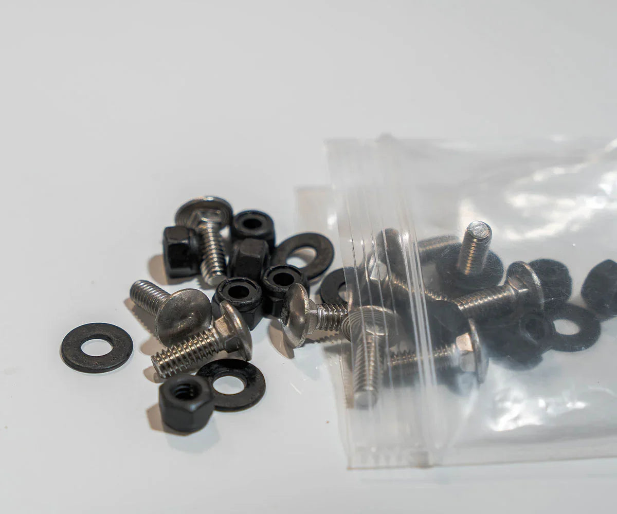 Assorted metal bolts, nuts, and washers for vehicle accessories on a white surface