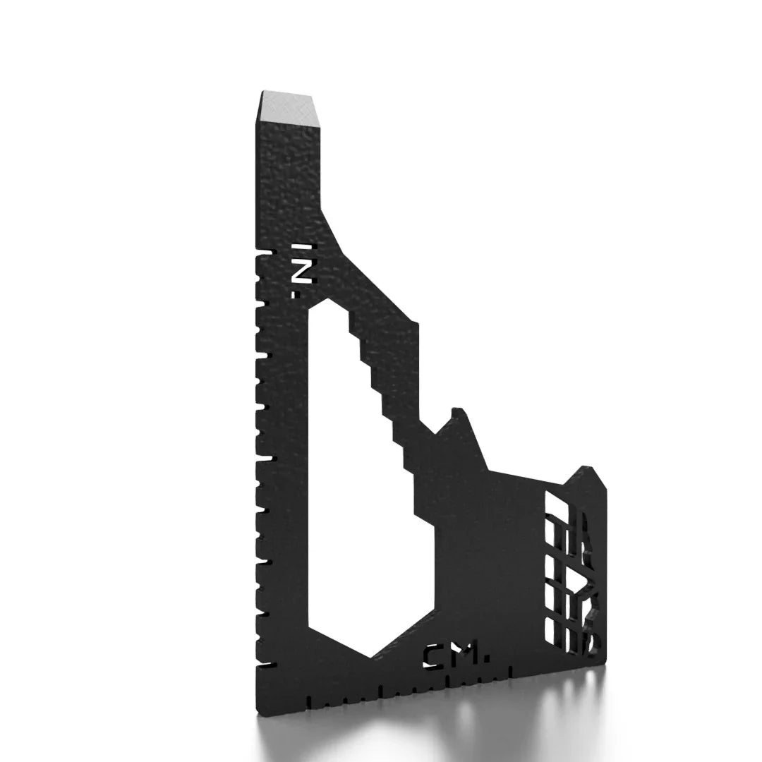 Black multi-purpose overlanding tool with metric and inch ruler markings on white background