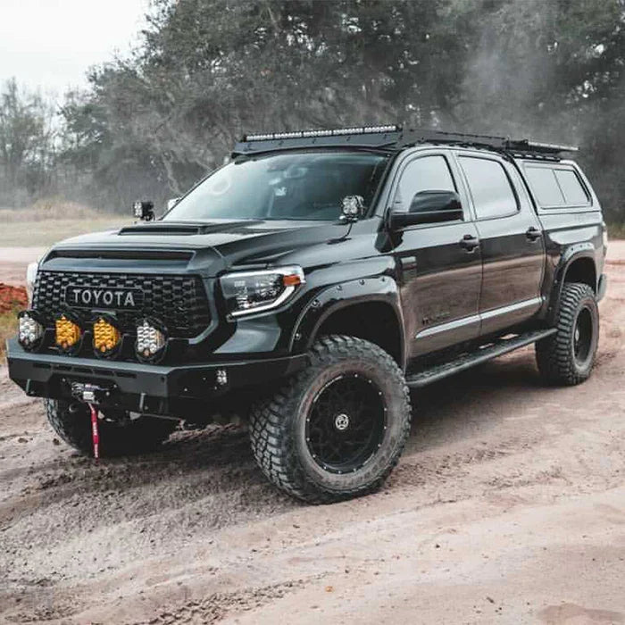 Lifted black Toyota Tundra with off-road accessories and roof rack on a dirt trail