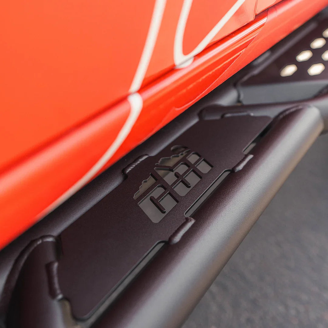 Closeup of off-road rock slider mounted on a red vehicle, rugged step plate detail
