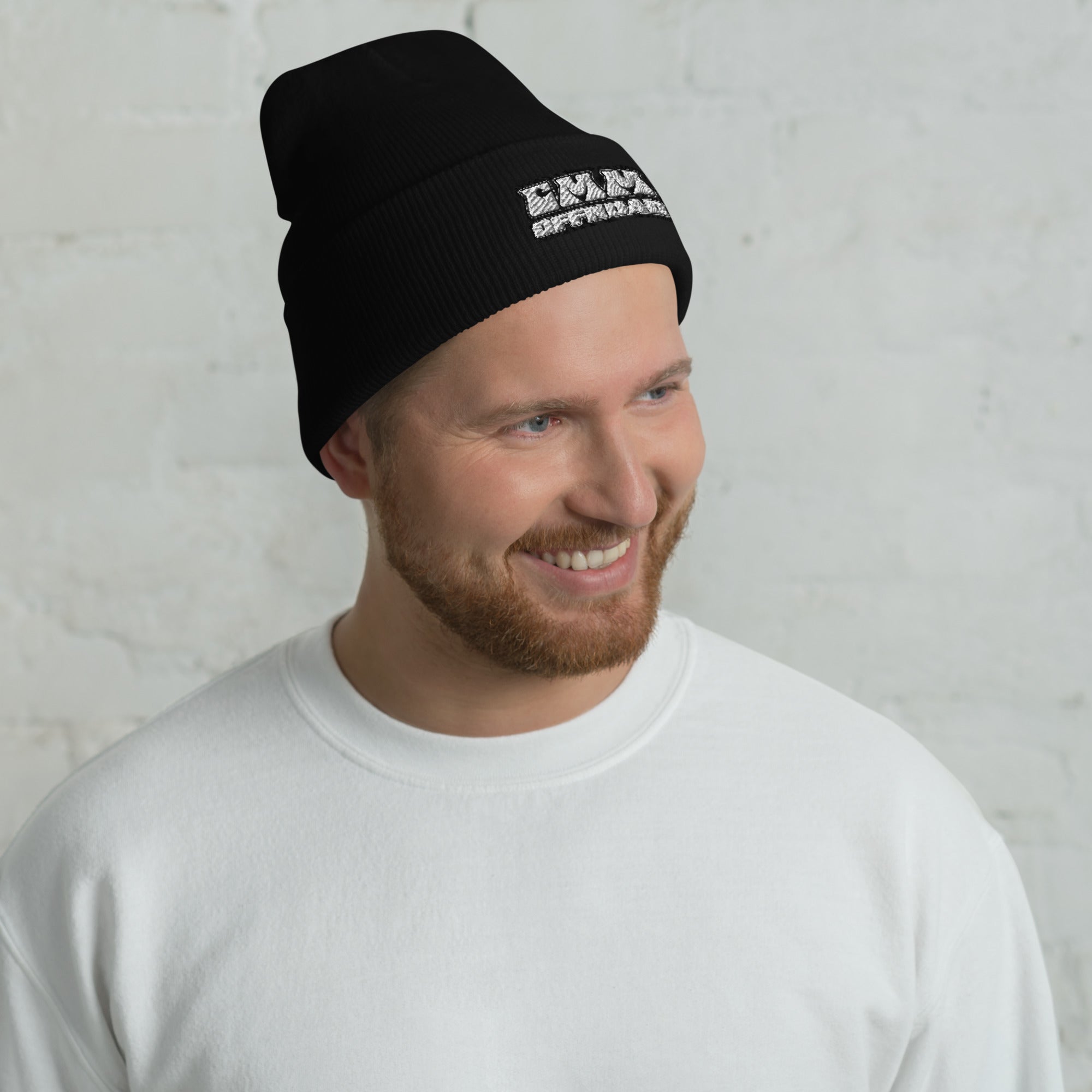 Man wearing black cuffed beanie with white lettering, casual outdoor adventure style