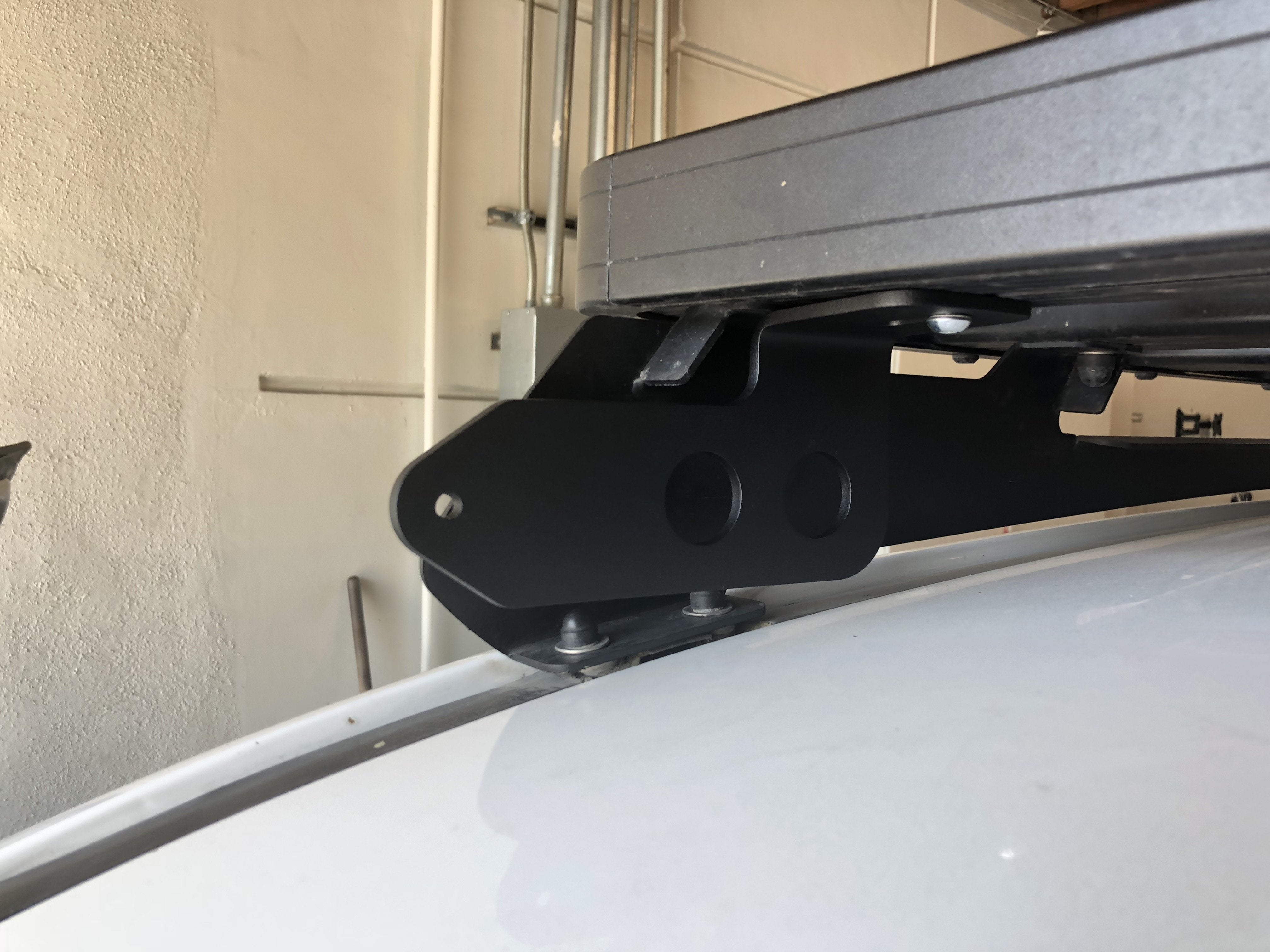 Heavy-duty roof rack mounting bracket installed on a white overlanding vehicle