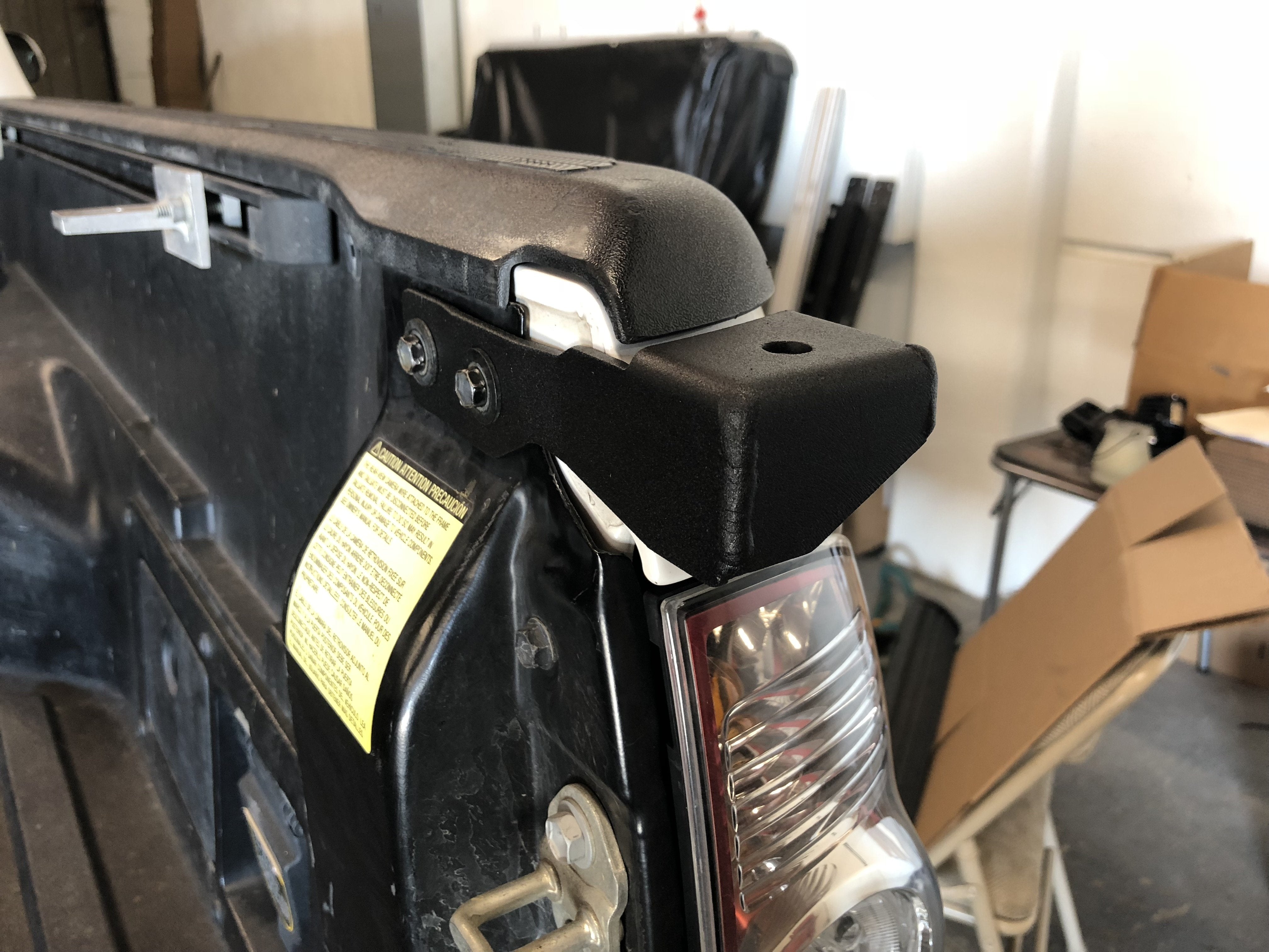 Truck bed corner guard installation on pickup tailgate with exposed bolts and rear light