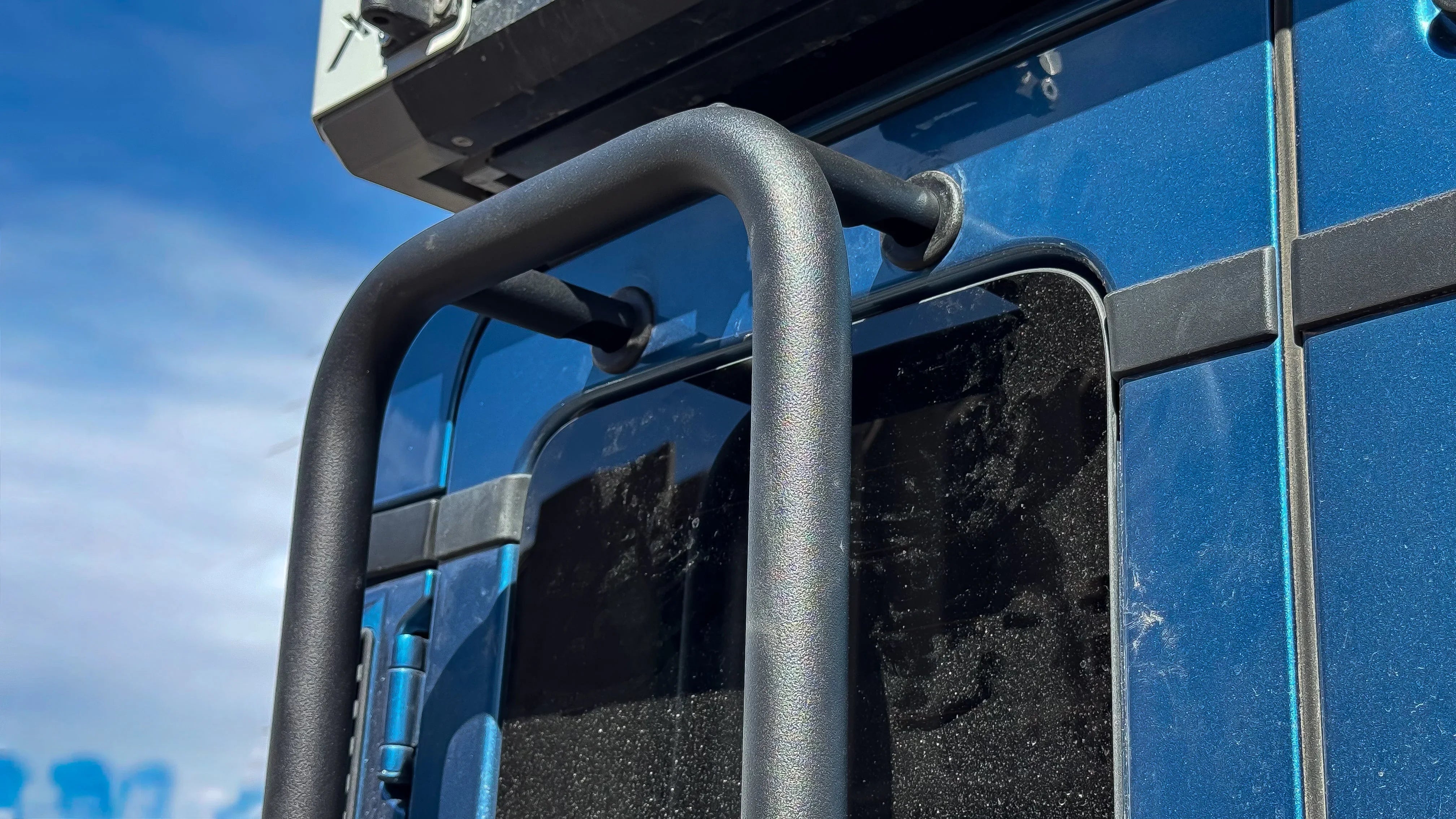 Close-up of rear ladder top mounting point on blue off-road vehicle