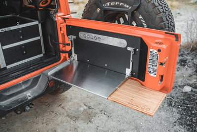 Goose Gear tailgate table folded down on an orange Jeep Wrangler JL, metal work surface and bamboo extension at the tailgate