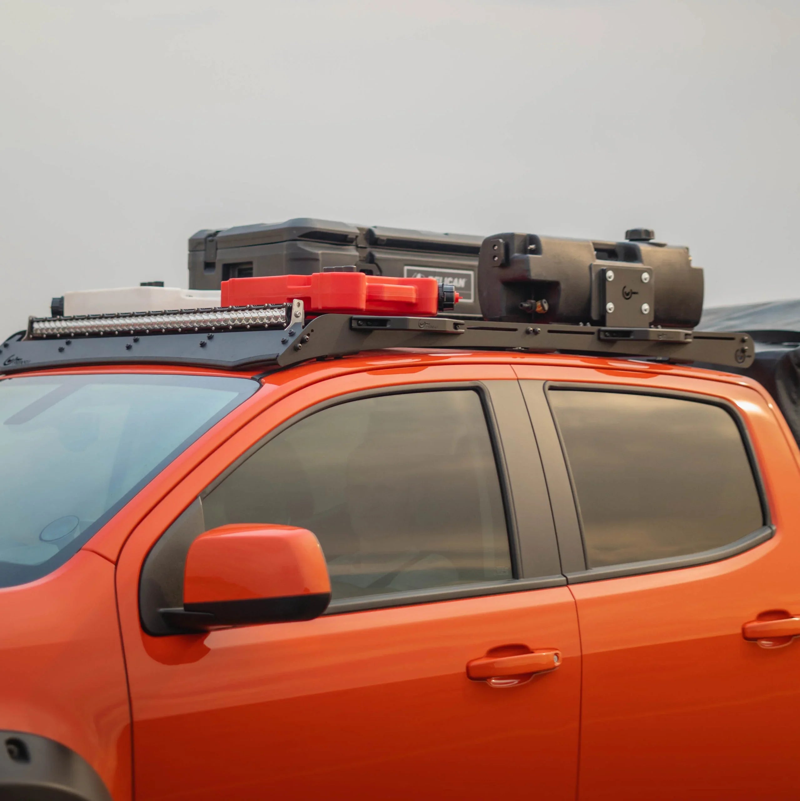 Overland vehicle roof rack loaded with gear boxes, fuel cans, and light bar