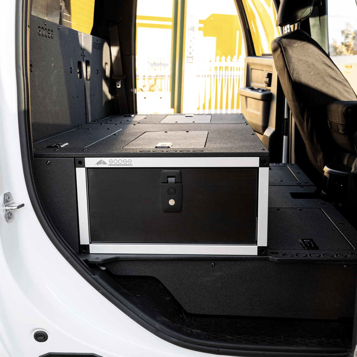 Goose Gear single drawer module with fitted top plate behind the front seat of a white Ram 2500/3500 Crew Cab