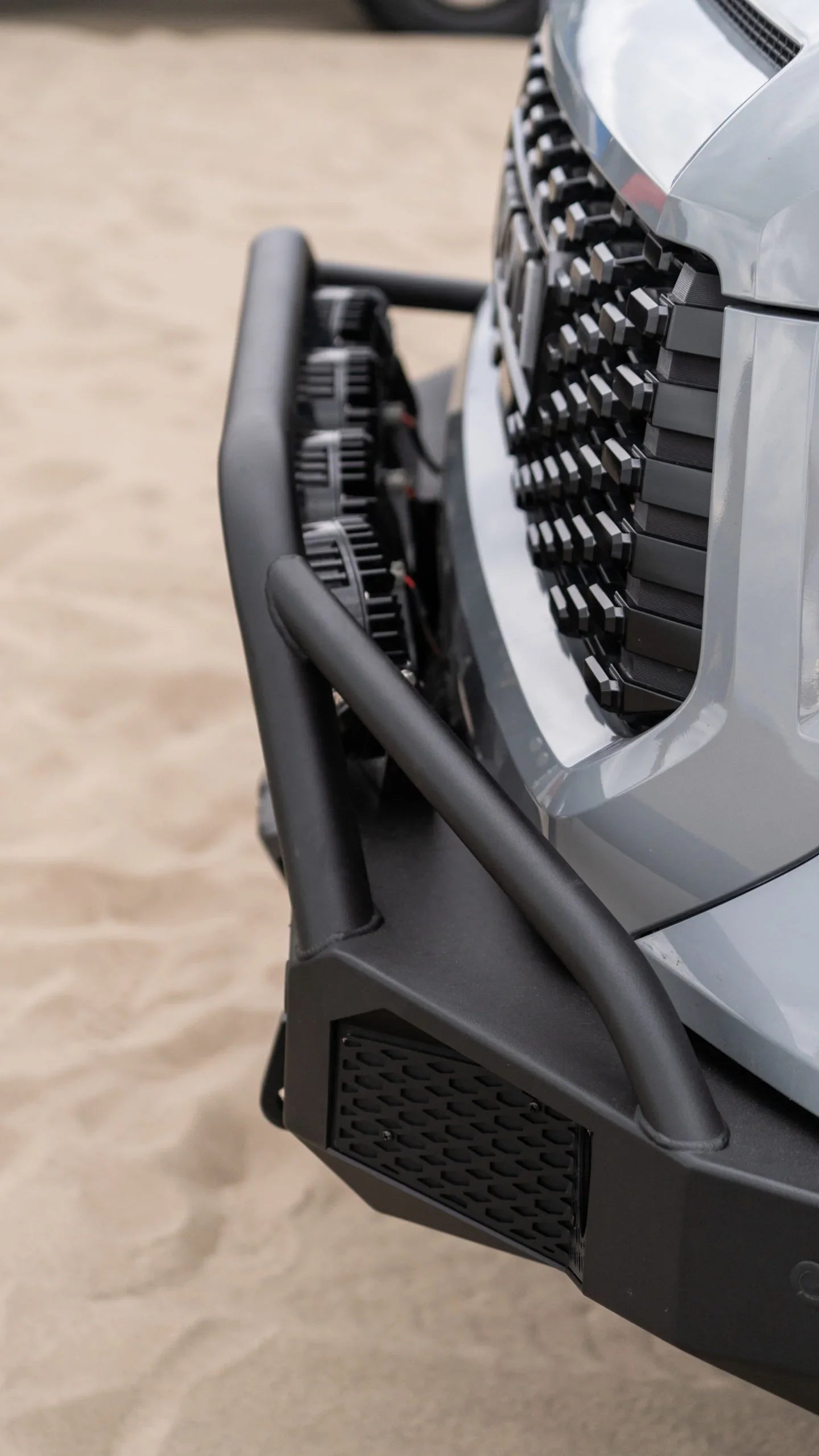 Off-road front bumper and grille on a silver vehicle parked on sand