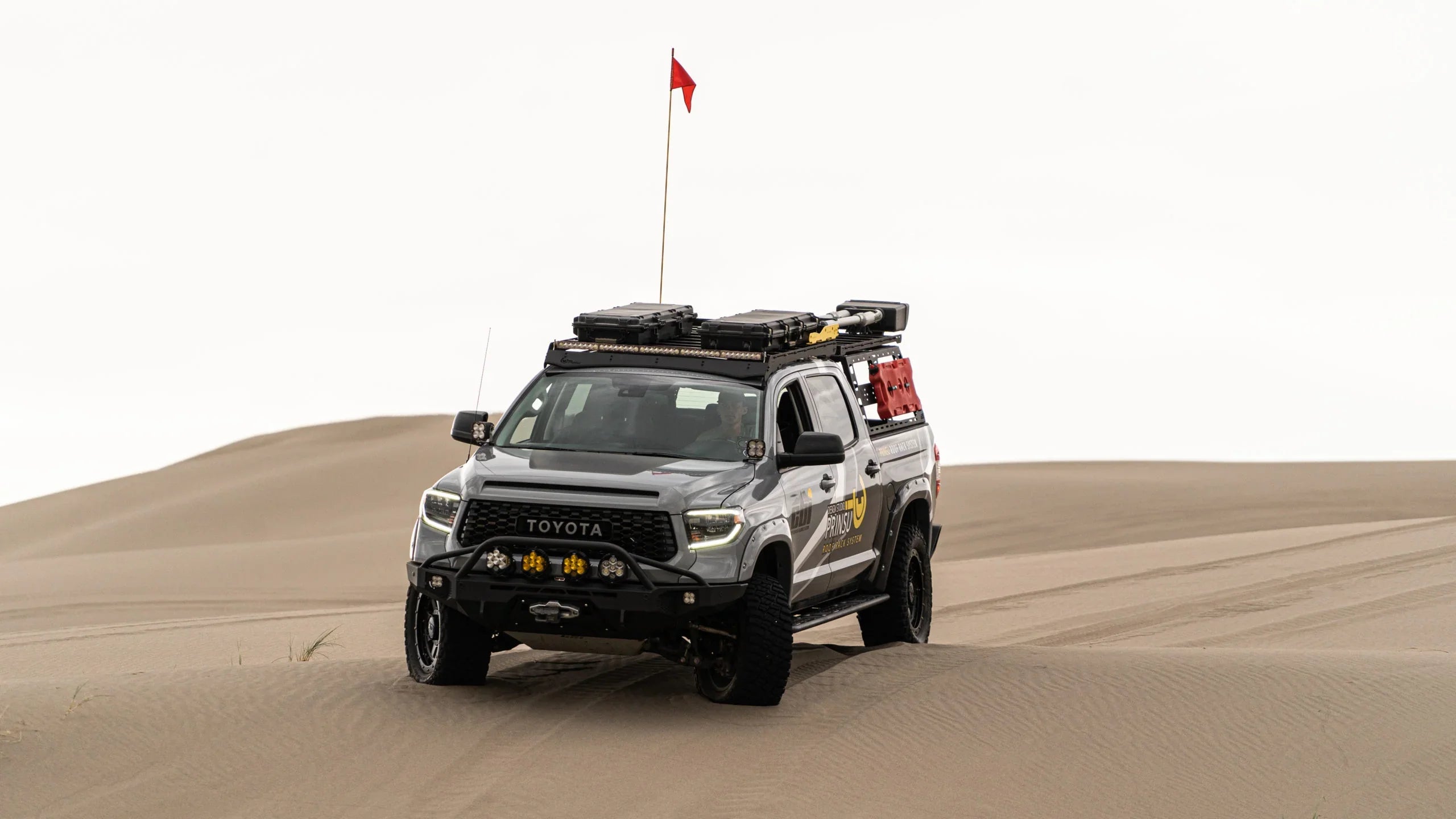 Toyota Tundra overland rig with roof rack and gear driving on sand dunes