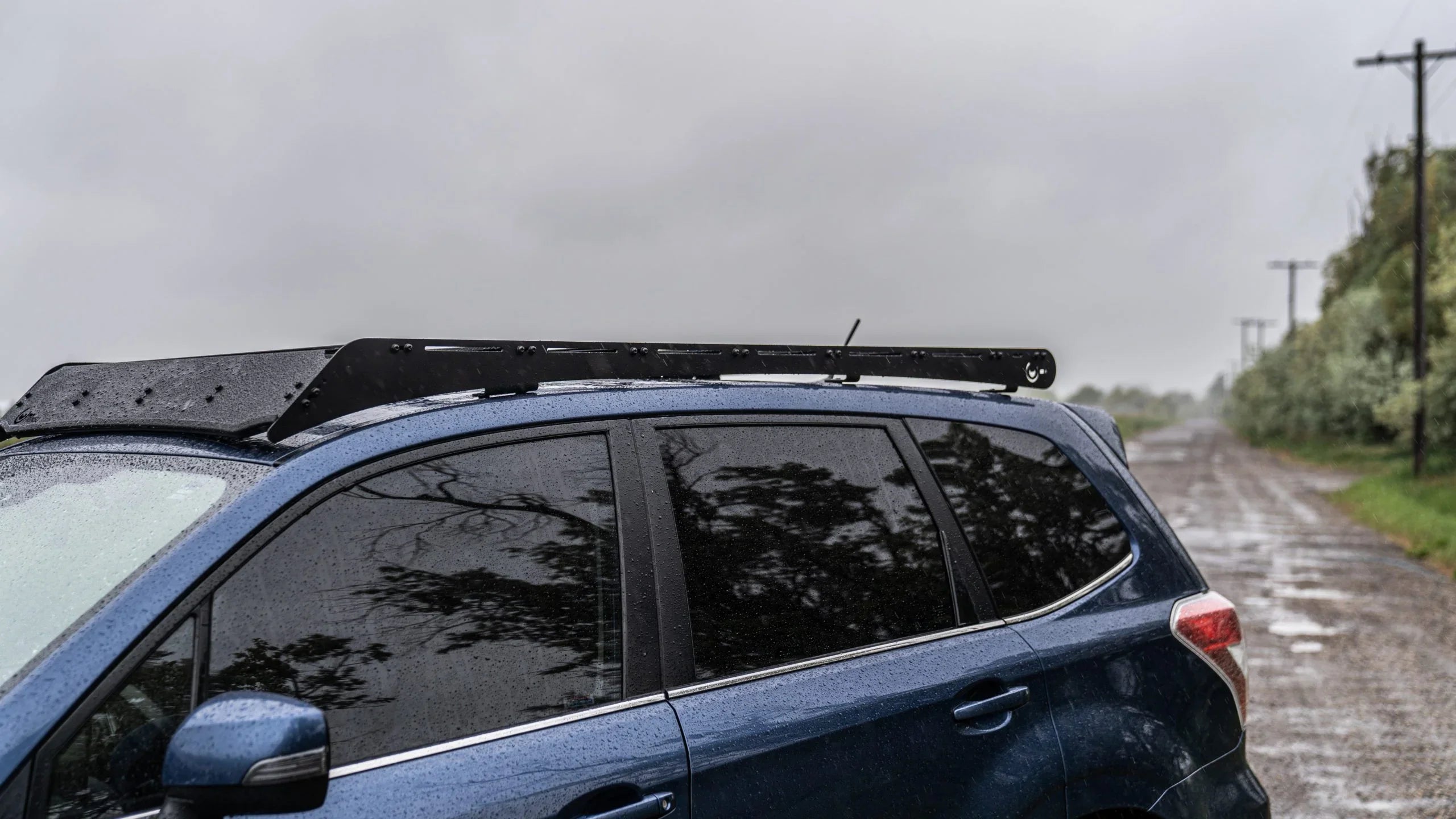 Subaru Forester with roof rack parked on a rainy dirt road, overlanding vehicle accessory