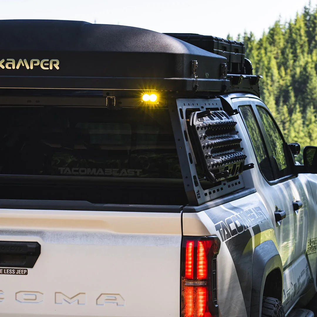 Toyota Tacoma with overland bed rack, gear storage mounts, LED lights, rooftop tent in forest