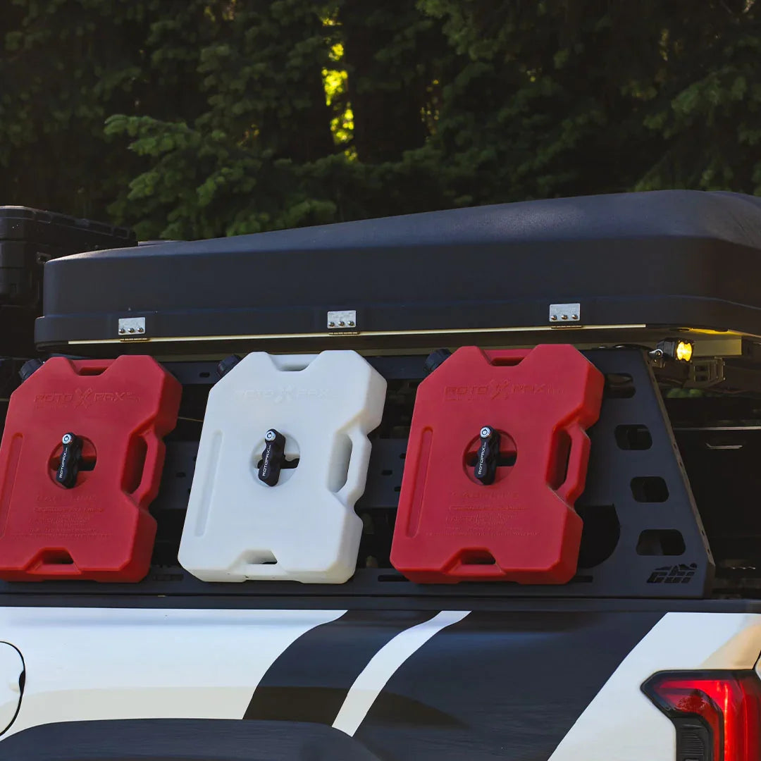 Truck bed rack with mounted red and white fuel containers, rooftop tent, outdoors