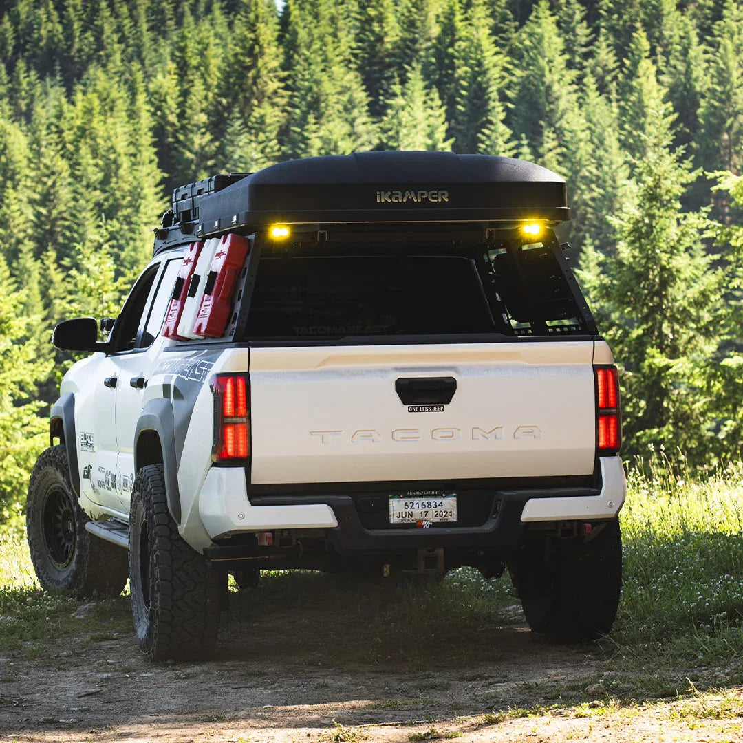 Toyota Tacoma with overlanding bed rack, rooftop tent, storage gear in forest setting