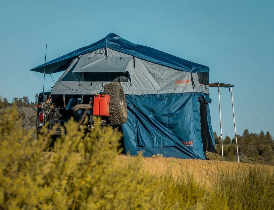 Overland vehicle with rooftop tent and awning set up for expedition camping in nature