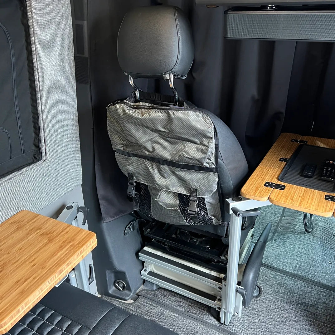 Vehicle seat with attached gray storage organizer and foldable table inside an overland camper