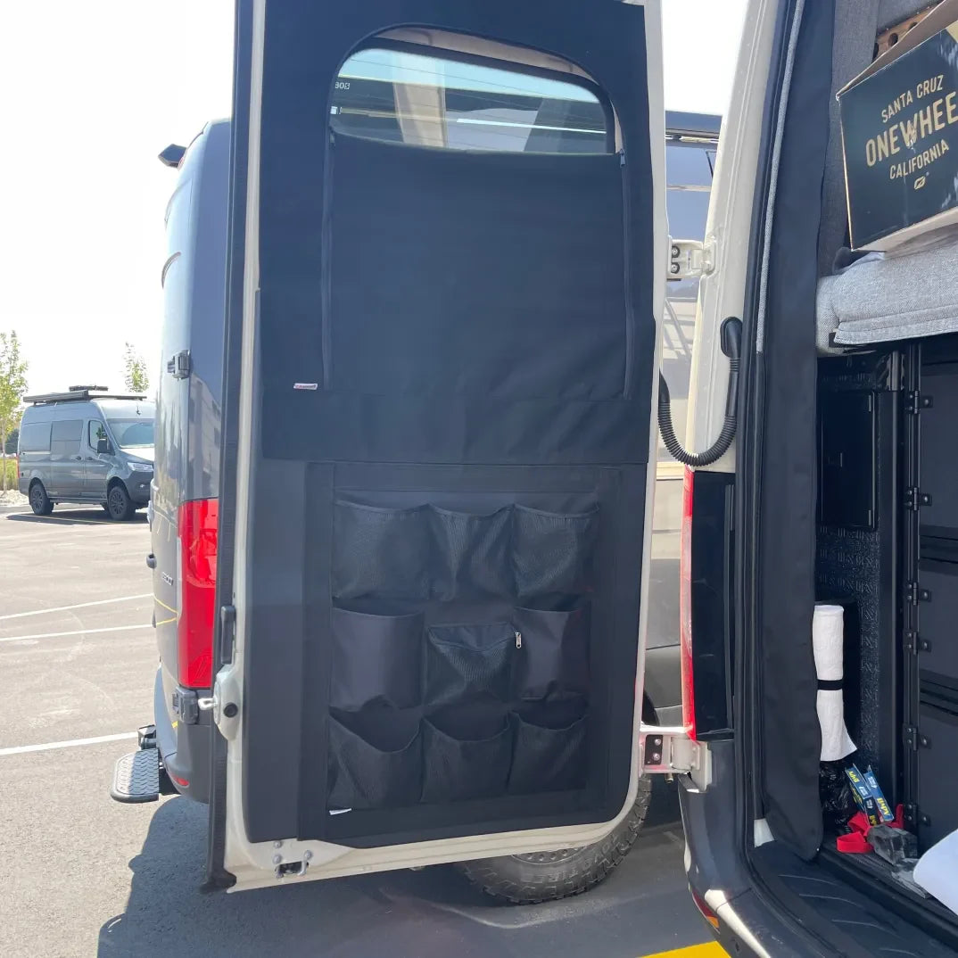 Van rear door with black storage organizer and mesh pockets, parked in outdoor lot