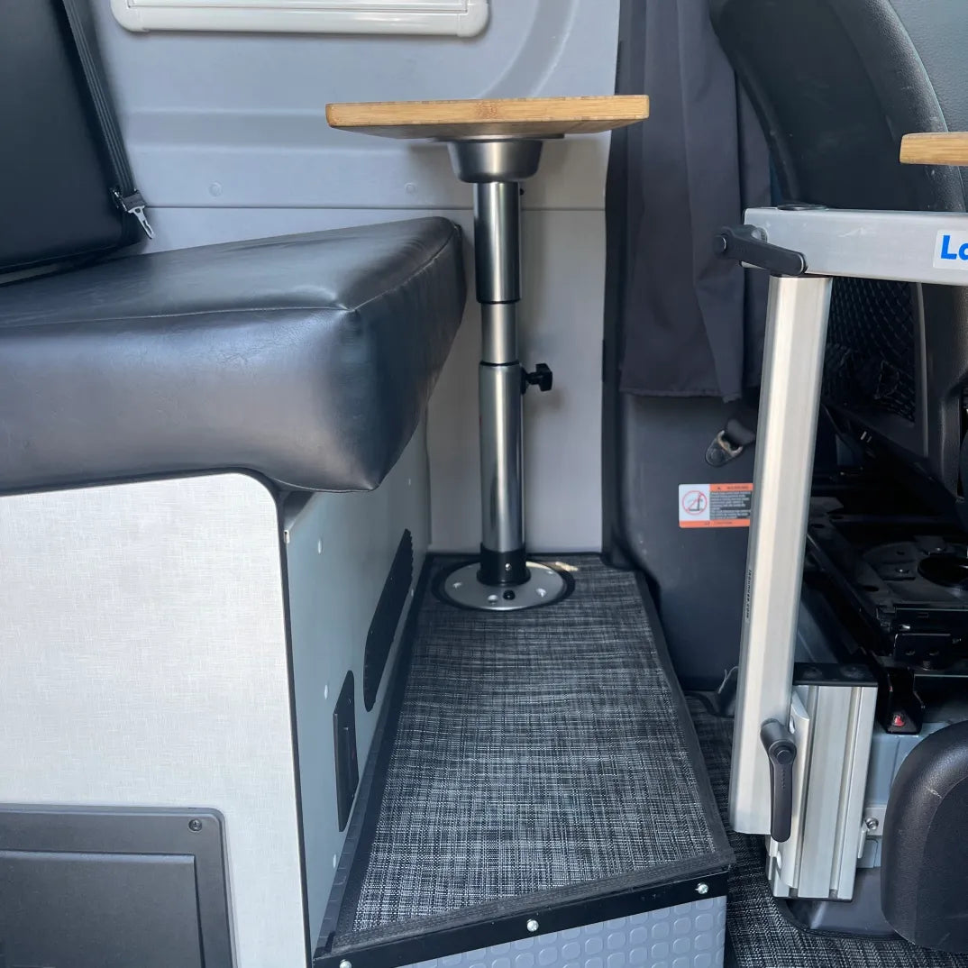 Compact campervan interior with adjustable table, cushioned seat, and storage compartments