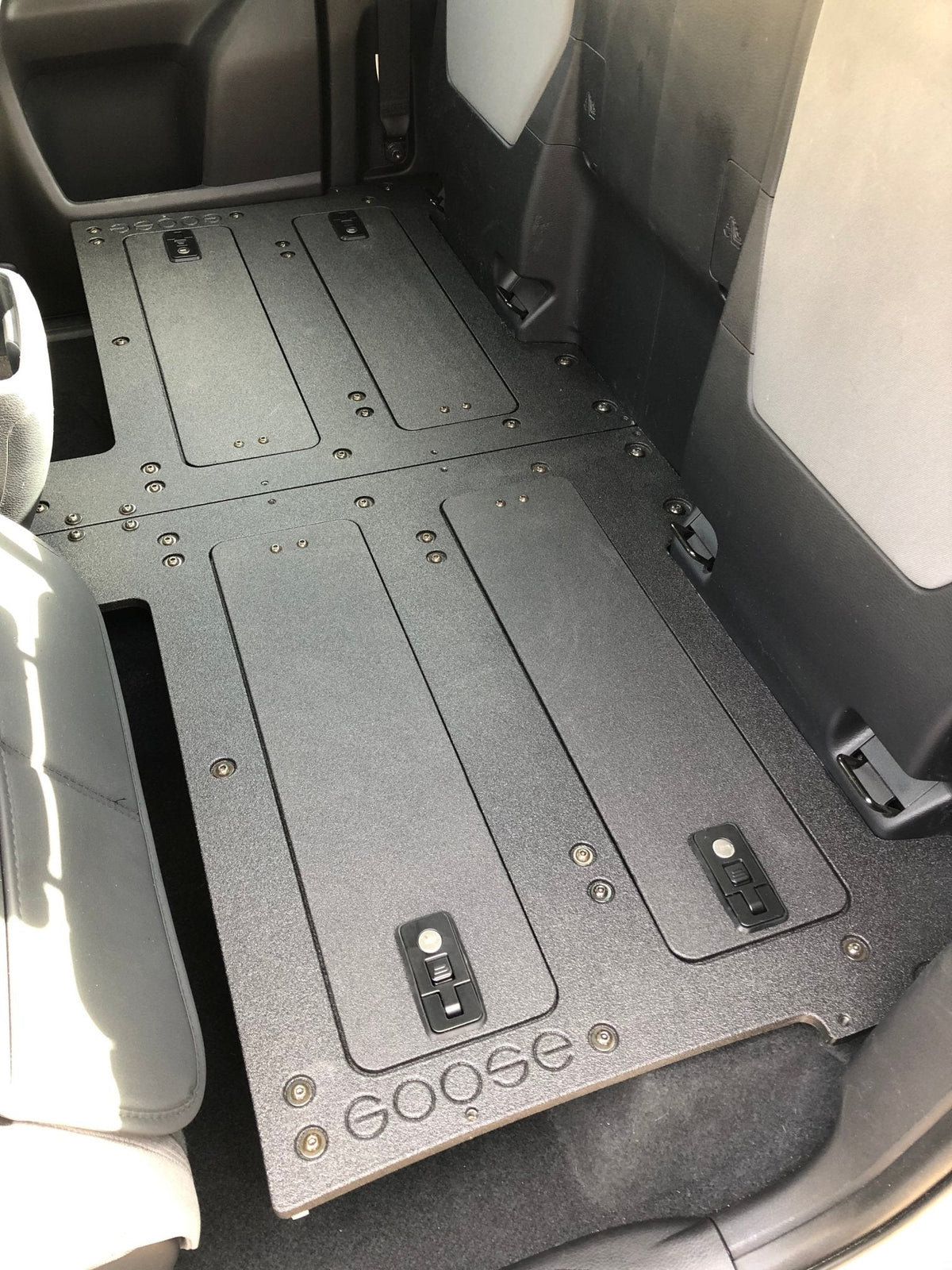 Goose Gear second row seat delete plate system in a 2016-2023 Toyota Tacoma Access Cab, black textured plates with latches