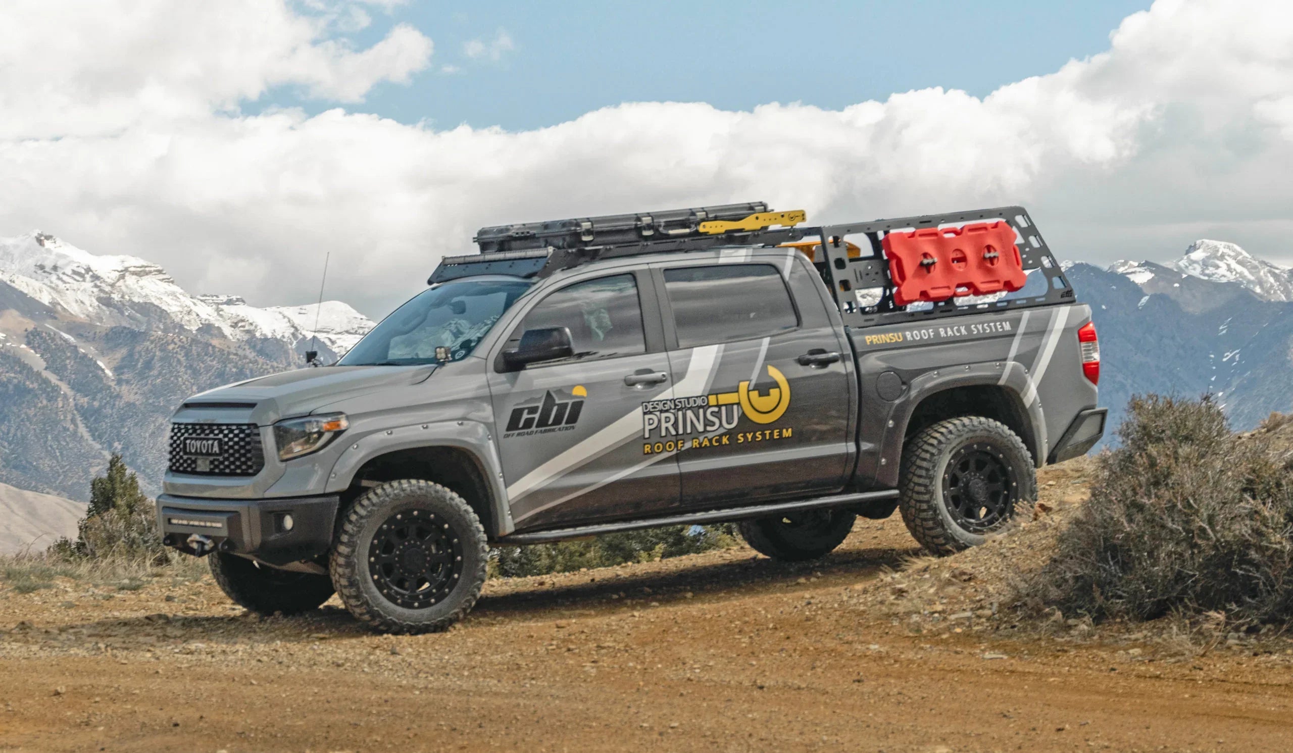 Toyota Tundra with high bed rack and roof rack system parked on mountain trail