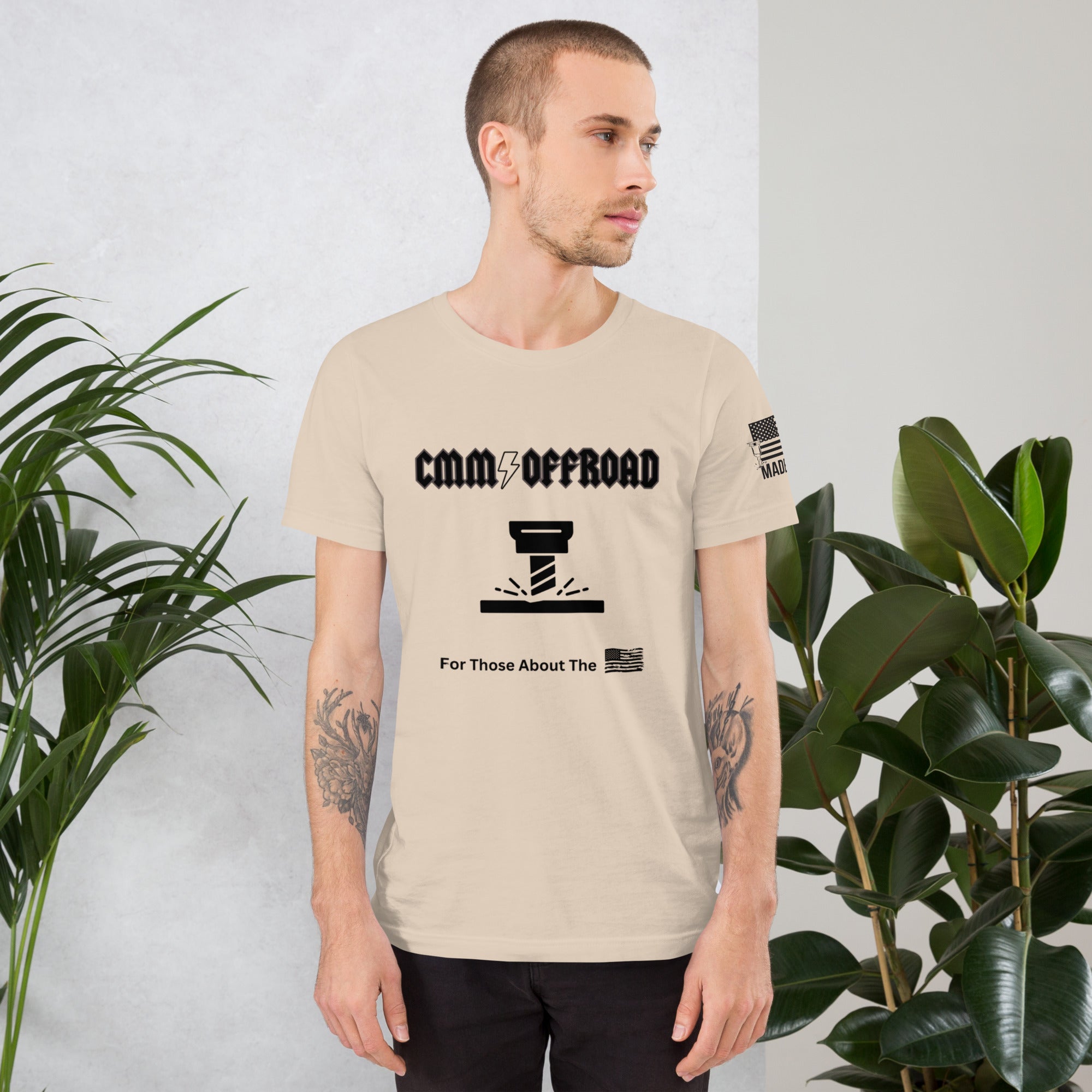 Man wearing soft cream unisex offroad graphic t-shirt standing indoors near plants